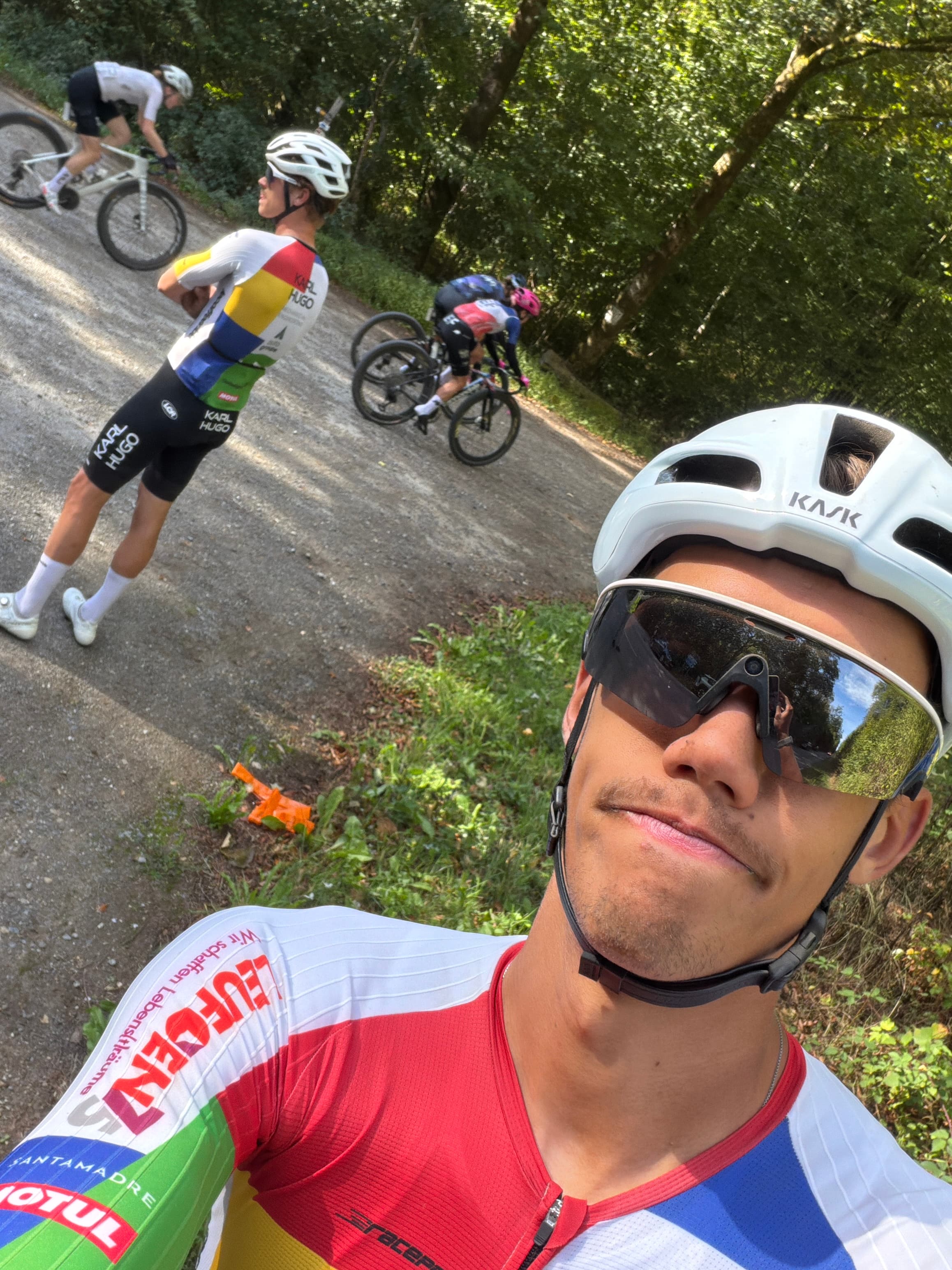 Donoven taking a roadside selfie with other cyclists in the background